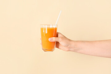 Female hand with glass of healthy juice on color background