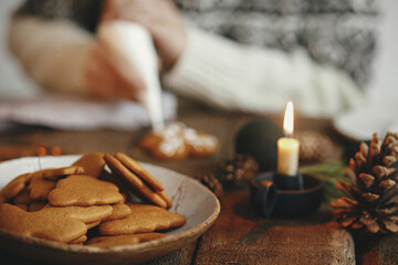 Freshly baked christmas gingerbread cookies in plate on background of rustic table with candle, spices, decorations. Moody image. Making traditional christmas gingerbread cookies. Happy Holidays