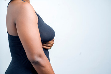 profile view of african lady with one hand under her breast- breast cancer awareness concept