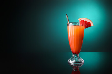 Glass of tasty Tequila Sunrise cocktail on dark color background