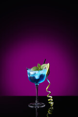 Glass of Blue Lagoon cocktail on dark color background