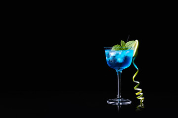 Glass of Blue Lagoon cocktail on dark background