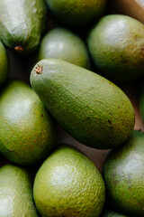 Lots of green fresh avocados in a box on the counter in the store,