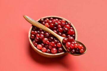 Bowl with spoon of tasty fresh cranberries on color background