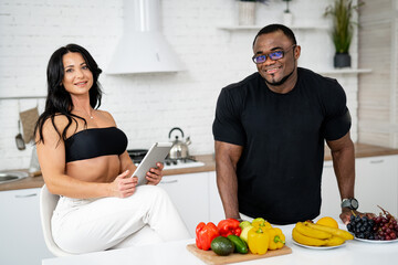 Healthy food at home. Happy couple is preparing vegetables and fruits in modern kitchen. Vegan and vegetarian lifestyle. Food for slimming