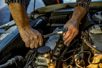 Fototapeta na wymiar Repairman's male hands with a wrench. Vehicle fitter inspecting used car engine
