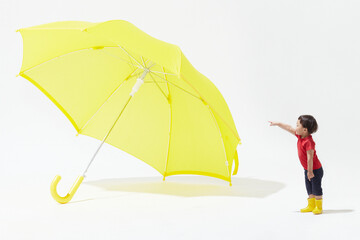 巨大な黄色の傘を指差す子ども