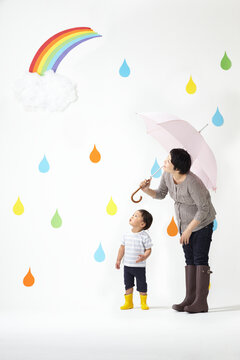 カラフルな雨のしずくバックで空を見上げるお母さんと子ども