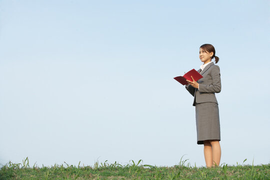 手帳を開き前を見つめるフレッシュなビジネスウーマン