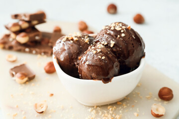 Bowl of tasty chocolate ice cream with nuts on white background