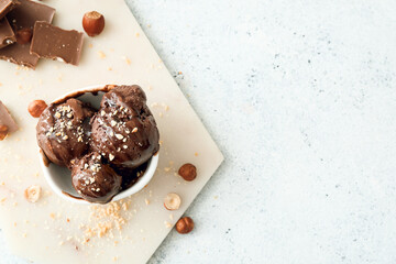 Bowl of tasty chocolate ice cream with nuts on white background