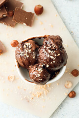 Bowl of tasty chocolate ice cream with nuts on white background