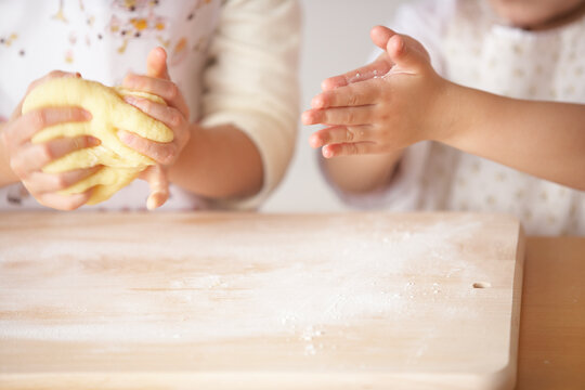 台所で小麦粉をこねてパン作りする女の子の姉妹