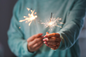 Woman with sparklers in room, closeup