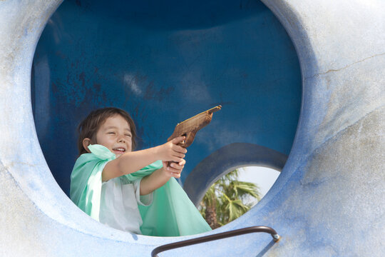 遊具の中でマントを着て鉄砲を撃つハーフの男の子