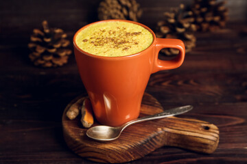 Cup of healthy homemade turmeric latte on wooden background, closeup