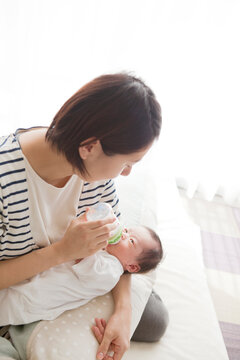 お母さんの腕に抱かれてミルクを飲んでいる男の子の赤ちゃん