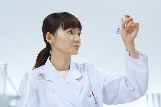 薬品の入った試験管を見つめている女性研究員