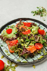 Delicious fresh salad with salmon on light background