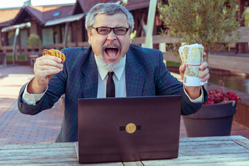 Man shows coins bitcoins and money paper cash, next to a laptop for working on the exchange. He...