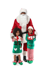 Little African-American children dressed as elves with Santa Claus and gifts on white background