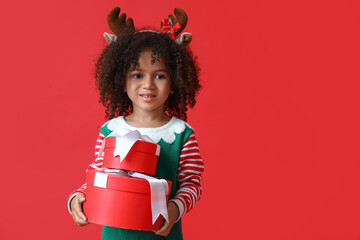 Little African-American girl with Christmas gifts on red background