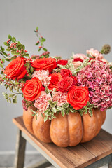 Obraz na płótnie Canvas Flowers arrangement in pumpkin on wooden table. Fresh cut flowers for decoration home. European floral shop. Delivery fresh cut flower.