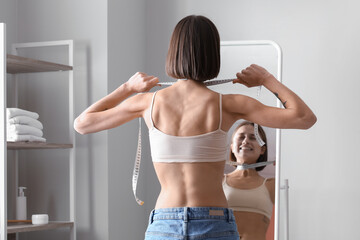 Young skinny woman in front of mirror at home. Anorexia concept