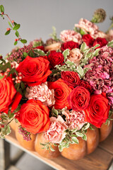 Flowers arrangement in pumpkin on wooden table. Fresh cut flowers for decoration home. European floral shop. Delivery fresh cut flower.