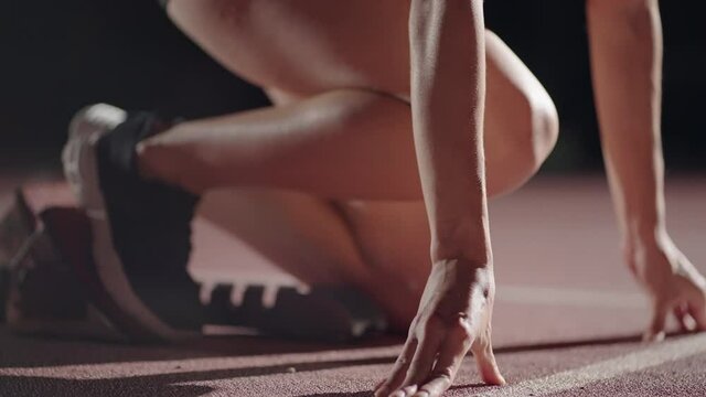slow motion female runner at the start close-up in the dark at the stadium professional runner athletic