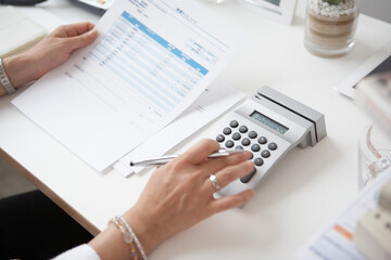 机で電卓で計算をする女性の手