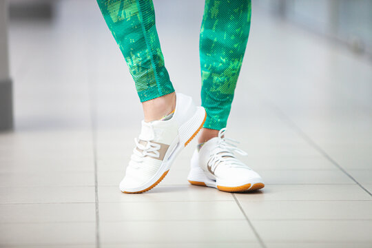 Women slender legs in sports leggings and sneakers in the gym.