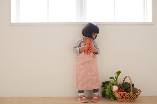 エプロンをして野菜を手に持つ女の子