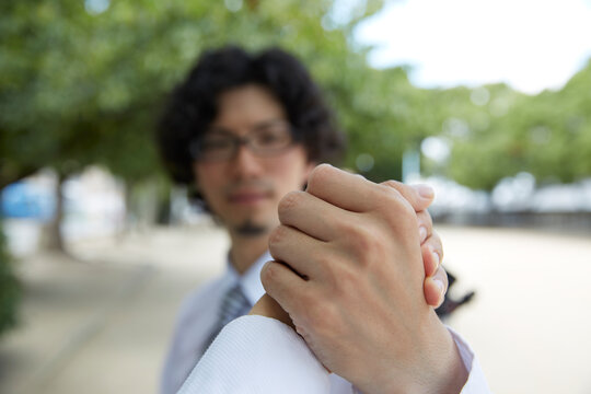 並木道で握手をするめがねの男性