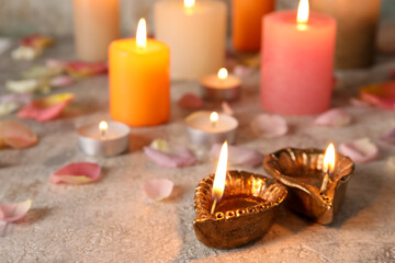 Diya lamps for Diwali, candles and flower petals on table
