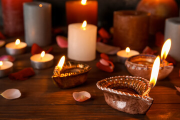 Diya lamps for Diwali, candles and flower petals on table