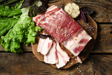 Board with uncooked bacon on wooden background - obrazy, fototapety, plakaty