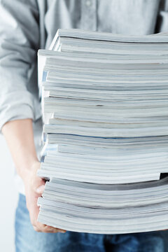 積み重なった雑誌を持つ人