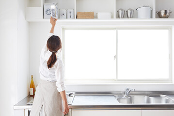 キッチンの戸棚から物を取る女性