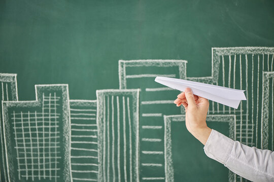 満月が描かれた黒板イラストの前で紙飛行機を飛ばす