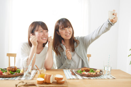 ダイニングテーブル上のコロッケとスマホで撮影する女性たち