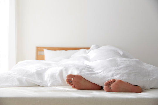 明るい光の入ったシンプルなベッドルームと眠る男性