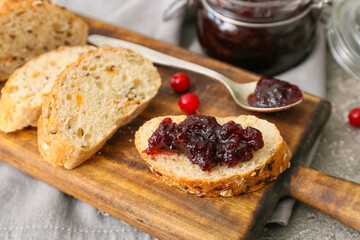 Wooden board of tasty toasts with lingonberry jam on grey background, closeup