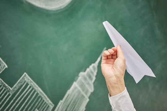 満月が描かれた黒板イラストの前で紙飛行機を飛ばす