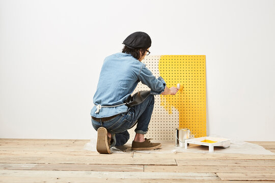 有孔パネルを塗る男性