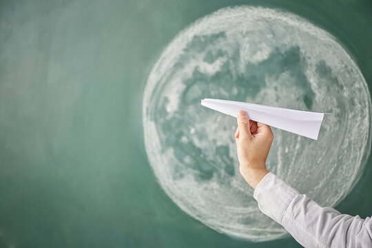 満月が描かれた黒板イラストの前で紙飛行機を飛ばす