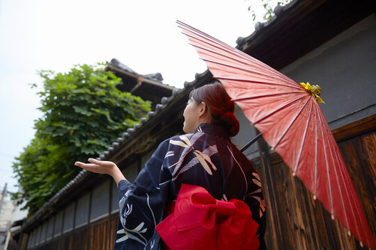 和傘を差して路地を歩く女性