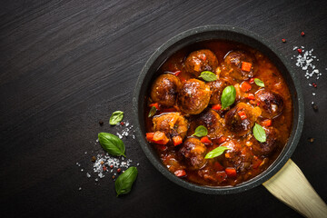 Meatballs in tomato sauce in a frying pan on dark stone table. Top view copy space.