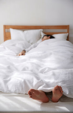 明るい光の入ったシンプルなベッドルームと眠る男性