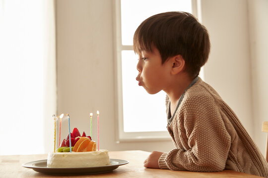 お祝いのケーキのろうそくの火を吹き消している男の子